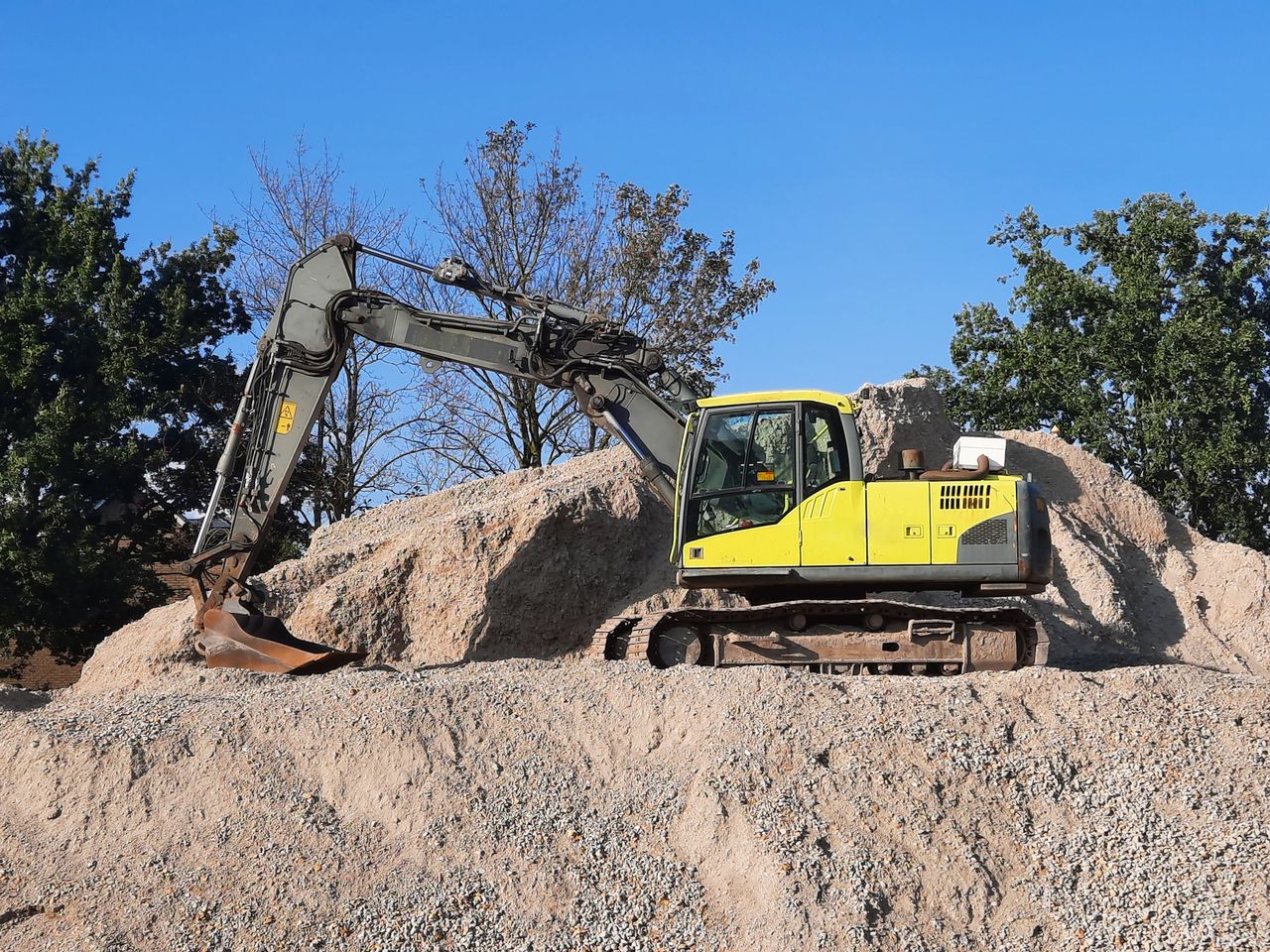 Mastering the First Impression: Your intriguing post title goes here A yellow excavator working on a gravel mound at a construction site.